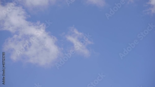 The plane flies among the clouds in the blue sky