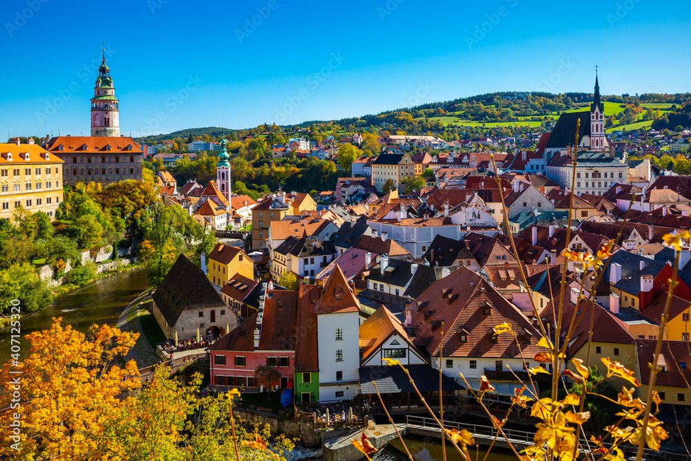 Scenic panoramic view of old part of Czech town of Cesky Krumlov with brownish tiled roofs of houses, medieval Castle and Cathedral of Saint Vitus
