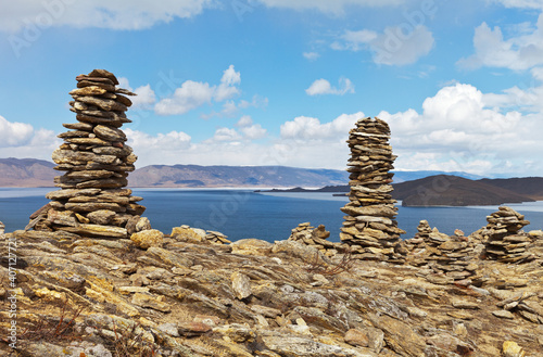 Lake Baikal on a sunny day in April. Stone pyramids on top of a rock against a blue sky. Ice drift in the Olkhonskiye Vorota (Olkhon Gate) Strait. Outdoor activities concept. Natural background