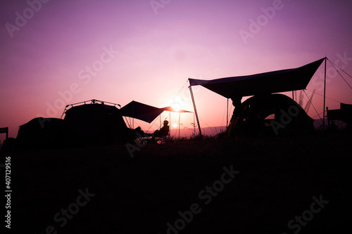Silhouette on sunrise, a group of tourists or adventurers with tent, travel to nature.