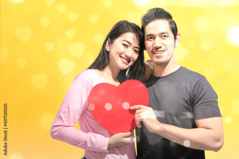 Asian couples holding the red heart with a yellow background
