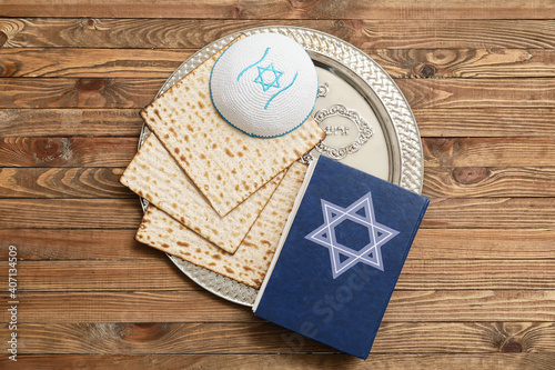 Passover Seder plate with matzo, Jewish cap and Torah on wooden background photo