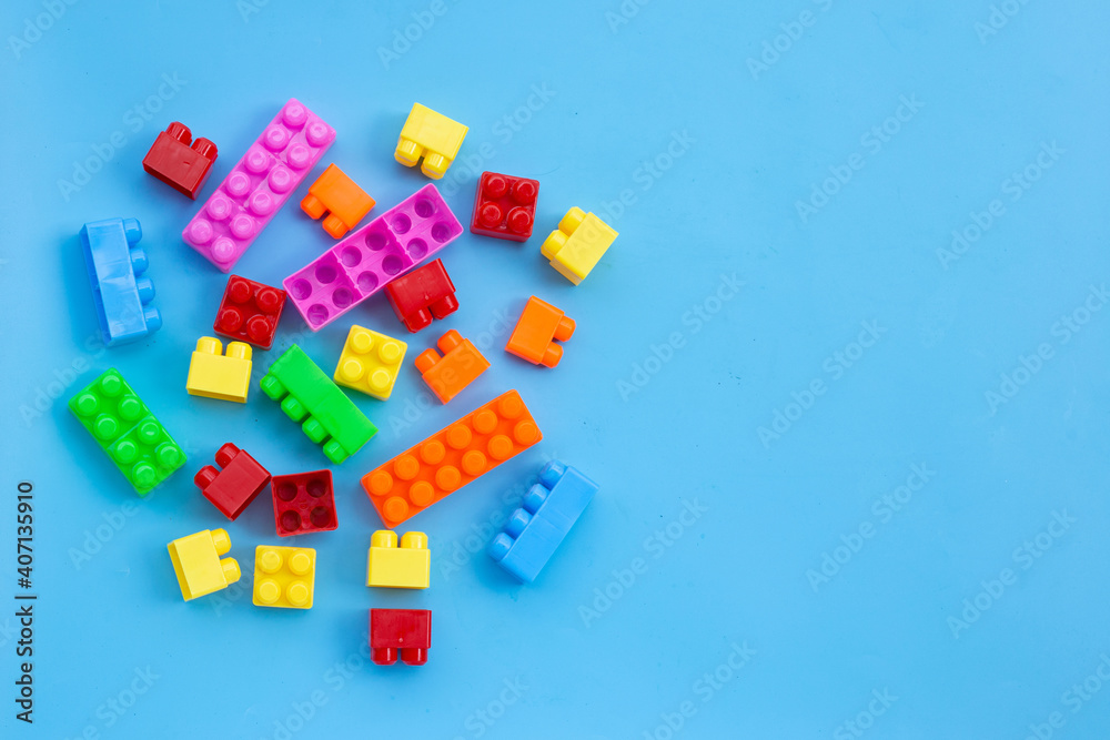 Plastic building blocks on blue background.