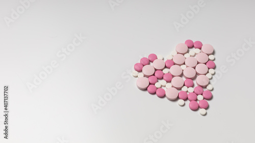 Heart of pink pills on a white background