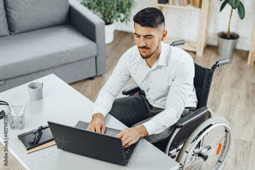 Foto Positive disabled young man in wheelchair working in office