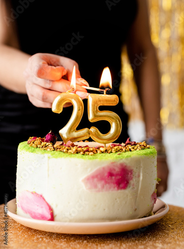 caucasian woman in black party dress lighting candles on birthday cake