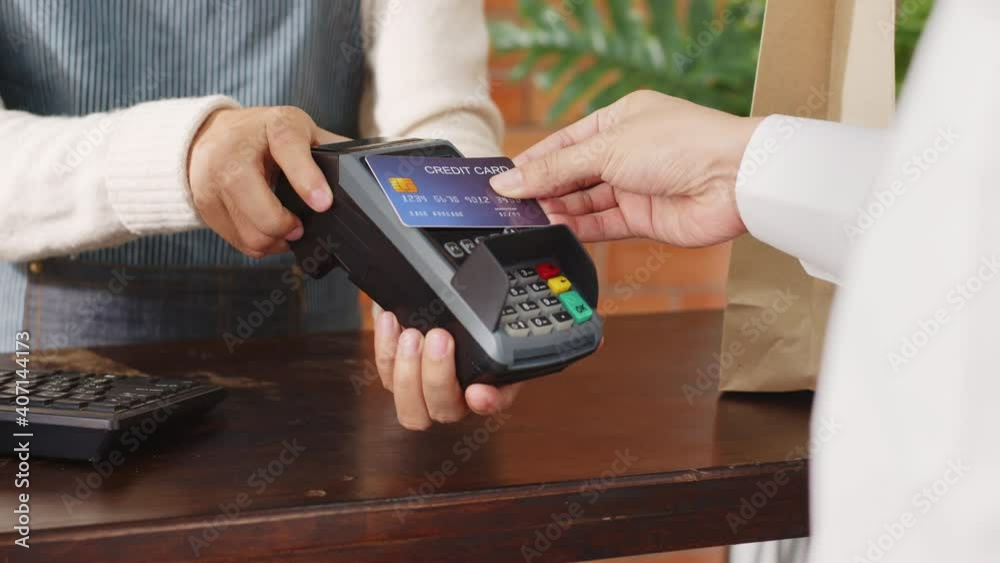 Customer using credit card for payment to owner at cafe restaurant, cashless technology and credit card payment concept