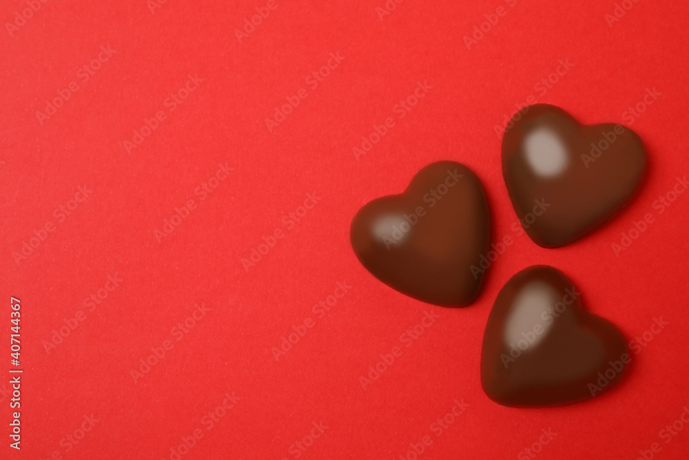 Chocolate hearts on red background, space for text