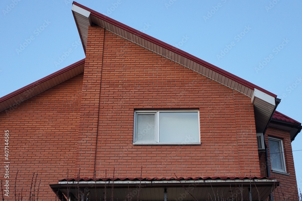 red brick loft of a private house with a white window against a blue sky