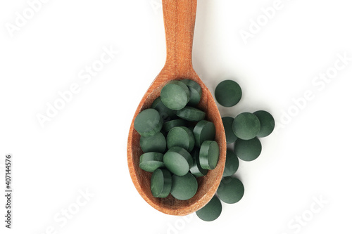 Wooden spoon with spirulina pills isolated on white background