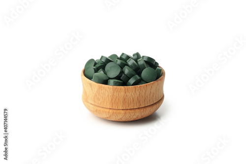 Wooden bowl with spirulina pills isolated on white background