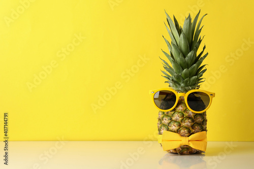 Pineapple with tie bow and sunglass against yellow background