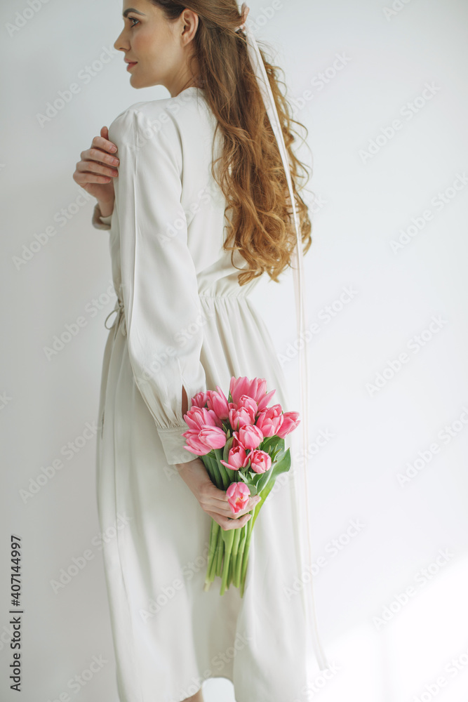 Attractive young woman in natural fabric dress holding a bouquet of tulips, isolated on white background. High quality photo. Attractive young woman in natural fabric dress holding a bouquet of tulips, isolated on white background. High quality photo.