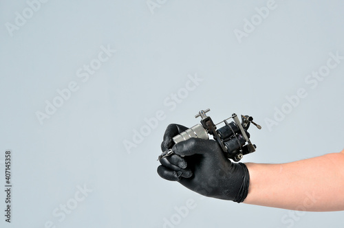 Hand in gloves holding tattoo machine