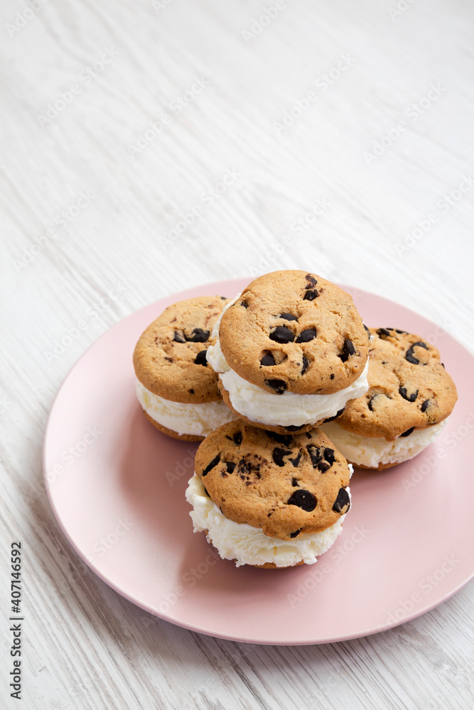 Homemade Chocolate Chip Cookie Ice Cream Sandwich on a pink plate on a white wooden surface, side view. Copy space. Homemade Chocolate Chip Cookie Ice Cream Sandwich on a pink plate on a white wooden surface, side view. Copy space.