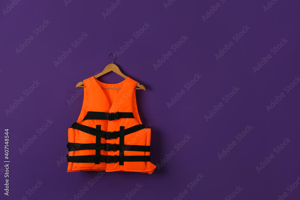 Orange life jacket on violet background. Space for text Orange life jacket on violet background. Space for text