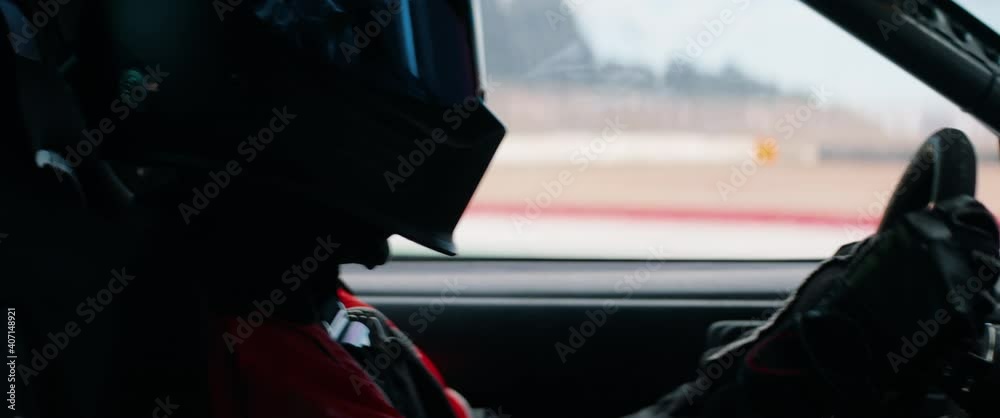 CU View of unrecognizable driver in protective wear driving a sports car, racing on a speedway. Shot with 2x anamorphic lens