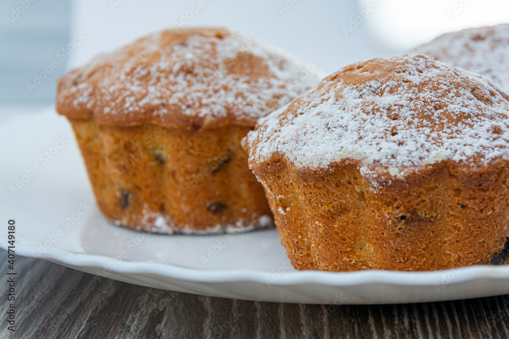 Cupcakes with raisins and powdered sugar on a plate. Close-up of confectionery. Image for project and design.