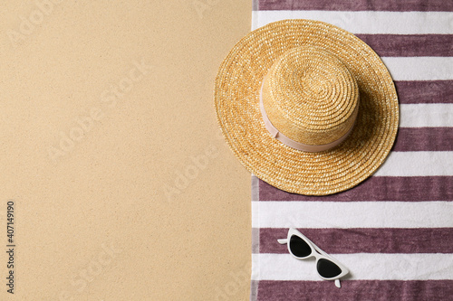 Fototapeta Naklejka Na Ścianę i Meble -  Straw hat, sunglasses, towel and space for text on beach sand, top view. Summer vacation