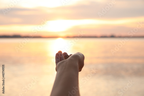 Young woman enjoying beautiful sunset near river, closeup. Nature healing power
