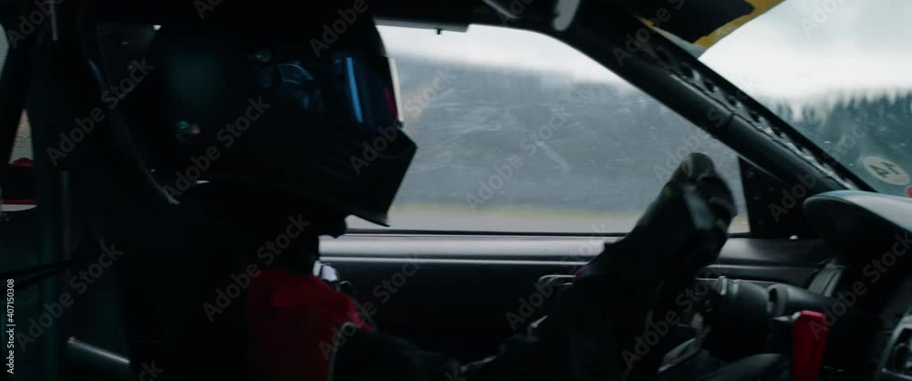 CU View of unrecognizable driver in protective wear driving a sports car, racing on a speedway. Shot with 2x anamorphic lens