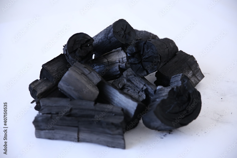 Black wood charcoal stacked on a white background.