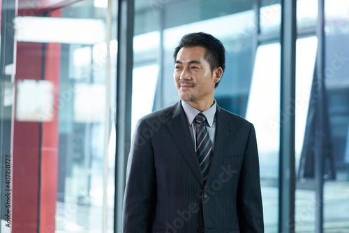 portrait of a mature asian business man walking in modern office