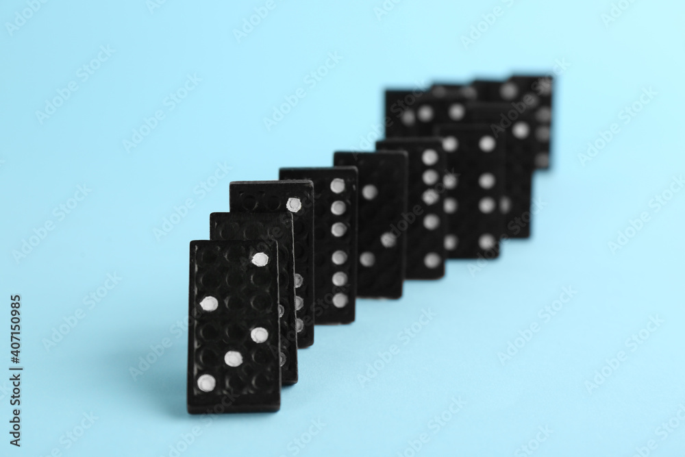 Black domino tiles falling on light blue background Black domino tiles falling on light blue background