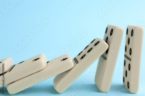 Obraz na plátně White domino tiles falling on light blue background, closeup