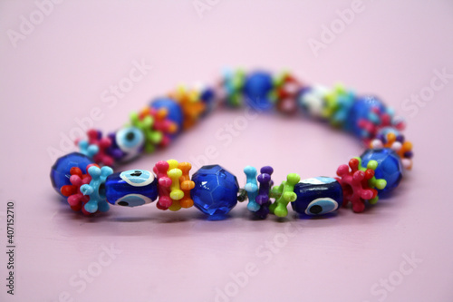 A bracelet made of beads on a pink background.