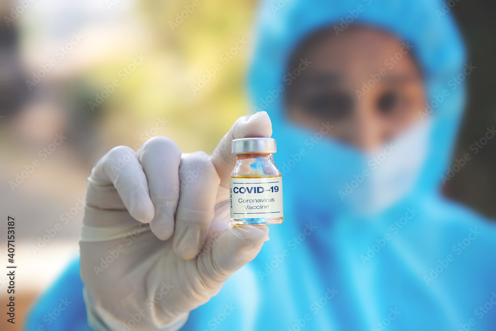 A doctor in medical gloves and mask holding an coronavirus vaccine. Coronavirus, epidemic and medicine concept.