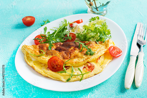 Breakfast. Omelette with tomatoes, cheese and arugula on white plate.  Frittata - italian omelet. Ketogenic, keto food.