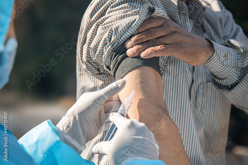 Photography Doctor's hands in surgical gloves preparing COVID-19 vaccine for male patient in