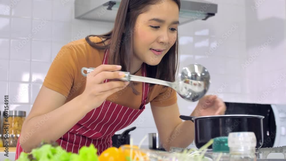 Young Asian woman cooking in kitchen at home. The wife is cooking a special meal for her husband. Young Asian woman cooking in kitchen at home. The wife is cooking a special meal for her husband.