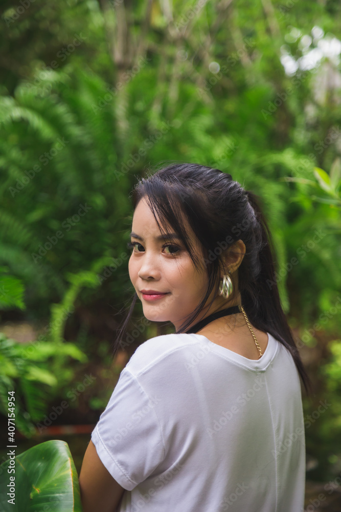 Close up portrait young Asian woman in white T-shirt looking at a camera with nature background. Close up portrait young Asian woman in white T-shirt looking at a camera with nature background.