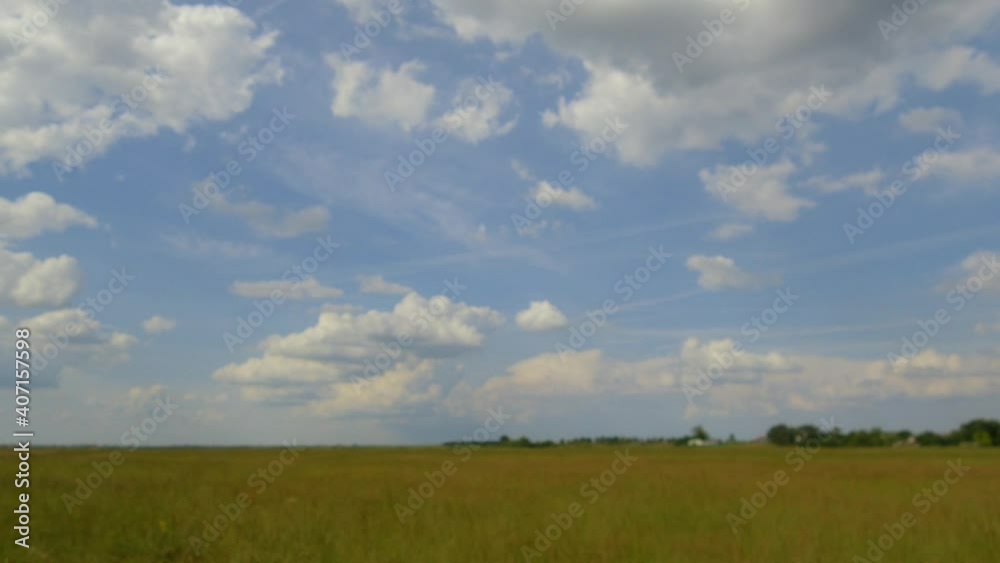 Stop motion video of white fluffy clouds moving above vast meadow.
Stop motion video of white fluffy clouds moving above vast meadow.