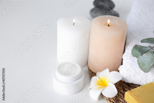 Composition with cream and burning candles on white table. Spa treatment