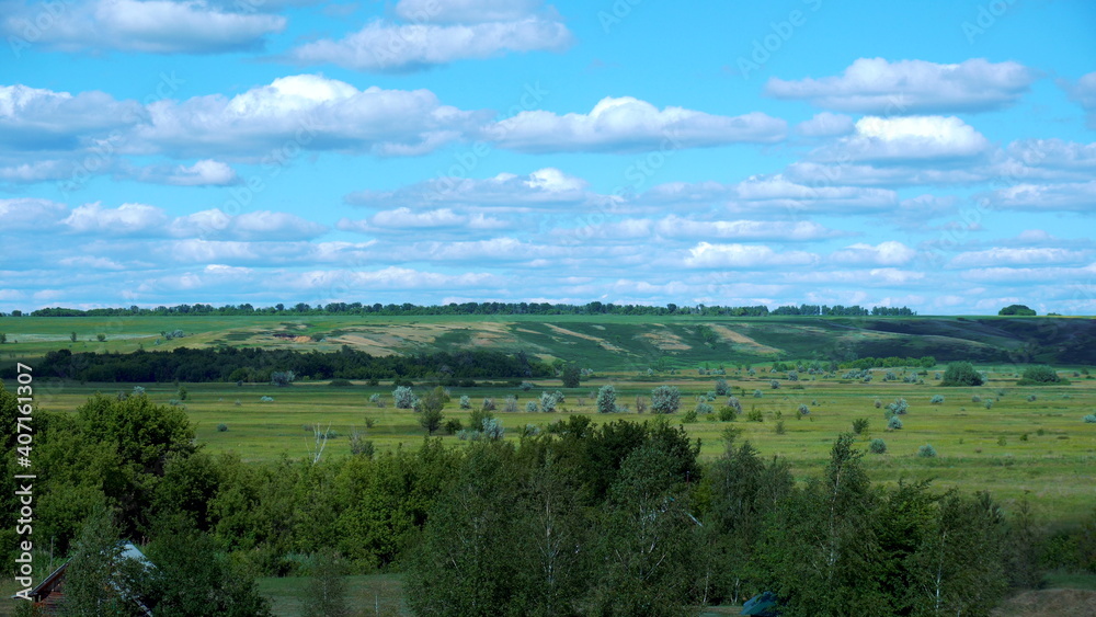 View of green fields and blue sky with clouds