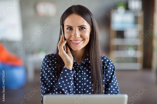 Photo of young attractive smiling cheerful positive good mood businesswoman talking hold smartphone working in office workplace