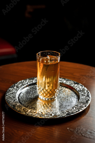 A long drink cocktail with ice in a vintage highball glass on a silver tray