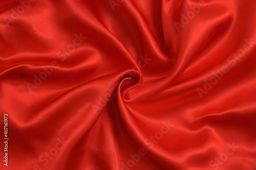 Background twisted red satin fabric with folds.
