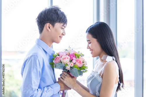 Valentine's day concept,asian Young happy sweet couple holding bouquet of red and pink roses After lunch In a restaurant background,Love story couple