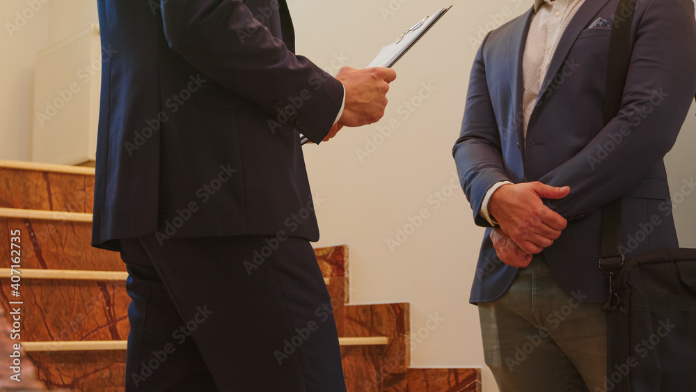 Fototapeta premium Close up of two business men in suit shaking hands standing on company stairs talking. Group of professional successful businesspeople working in modern financial workplace.