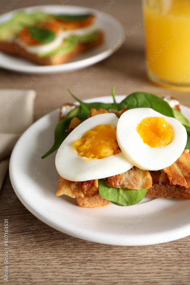 Sandwich with egg, bacon and spinach served on wooden table, closeup