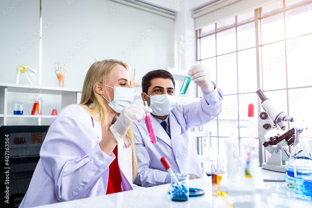 Two scientists are working holding looking at test tube with sample in a chemistry lab scientist or young female and male researcher are doing investigations in Laboratory analysis background Two scientists are working holding looking at test tube with sample in a chemistry lab scientist or young female and male researcher are doing investigations in Laboratory analysis background