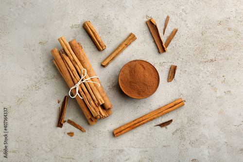 Fototapeta Naklejka Na Ścianę i Meble -  Aromatic cinnamon sticks and powder on grey table, flat lay