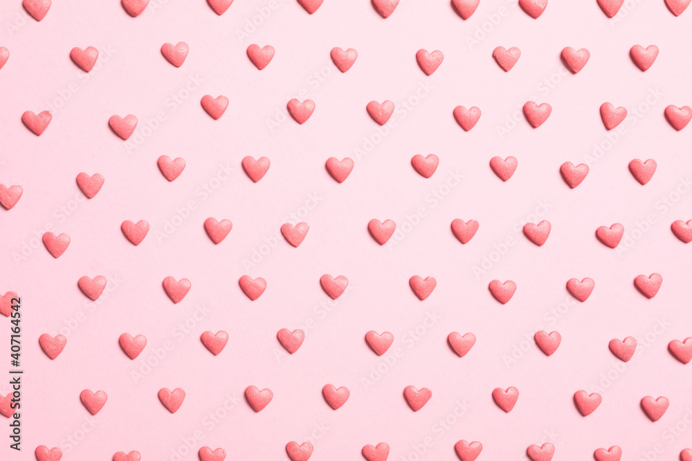 Tasty bright heart shaped sprinkles on pink background, flat lay