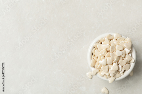 White heart shaped sprinkles in bowl on light grey table, flat lay. Space for text