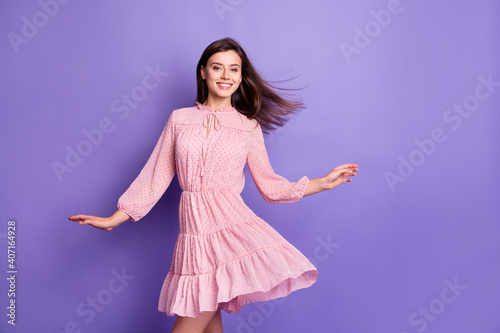 Portrait of pretty elegant cheerful girl wearing pink dress air blowing hair dancing isolated over bright violet color background