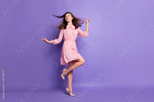Full length body size view of pretty cheery girl dancing relax wind blowing hair isolated over bright violet color background